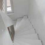 White spiral staircase with metal railing and skylight.