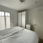 Bedroom with bed, wardrobe, and window with blinds.