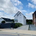 White single-family house with balcony and paved path.