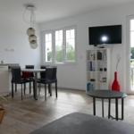 Living and dining area with TV, table, chairs, and balcony access.