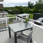 Terrace with table, chairs, and view of green areas.
