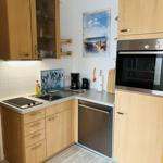 Küche mit Holzschränken, Spüle, Herd, Kühlschrank und Backofen.