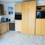 Küche mit Holzmöbeln, Spülmaschine und eingebauter Mikrowelle.