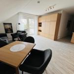 Wohn- und Essbereich mit Küchenzeile und Schlafzimmer im Hintergrund.