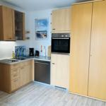 Küche mit Holzschränken, Spüle, Backofen und Kühlschrank.