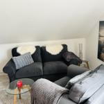 Schwarzes Sofa mit Fellkissen und graue Sitzgelegenheit mit Decke.