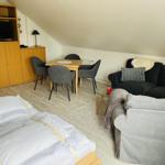 Wohnzimmer mit Sofa, Esstisch und Bett unter Dachschrägen.