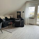 Wohnraum mit Sofa, Sessel und Balkonansicht
