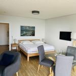 Zimmer mit Doppelbett, Esstisch, Fernseher und Wandbild.