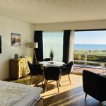 Schlafzimmer mit Blick aufs Meer und Essbereich mit Tisch und Stühlen.