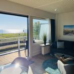 Wohnzimmer mit Meerblick, Sofa, Tisch und Balkon.