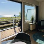 Wohnbereich mit Blick aufs Meer und Balkon mit Sitzgelegenheit.