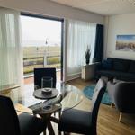 Wohn- und Essbereich mit Blick aufs Meer. Sofa, Tisch und Stühle.