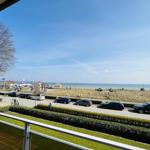 Blick von Balkon auf Strand mit Autos und Meer