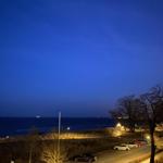 Nachtansicht vom Strand mit geparkten Autos und sternenklarem Himmel.