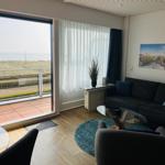 Wohnzimmer mit Blick aufs Meer und Balkon. Sofa, Sessel und Tisch.