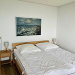 Schlafzimmer mit Doppelbett, Nachttisch und Wandbild.