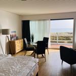 Schlafzimmer mit Blick aufs Meer und Essbereich mit Tisch und Stühlen.