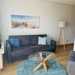 Wohnzimmer mit Sofa, Glas-Tisch und Wandbild