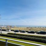 Blick auf Strand mit Parkplatz und Grünflächen unter blauem Himmel