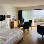 Schlafzimmer mit Blick aufs Meer und Essbereich mit Tisch und Stühlen.