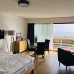 Schlafzimmer mit Blick aufs Meer und Essbereich mit Tisch und Stühlen.