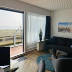 Wohnzimmer mit Blick auf Strand und See. Sofa, Tisch und Sessel.