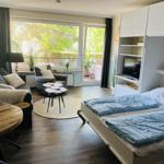 Ein Schlafzimmer mit Bett, TV und Balkonzugang.