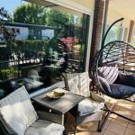 Terrasse mit Sitzgruppe, Hängesessel und Blick auf Garten.