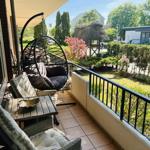 Terrasse mit Hängesessel und Sitzgruppe, Blick auf grünen Garten mit Hütte.