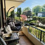 Terrasse mit Hängesessel, Tisch und Stühlen. Blick auf grünen Garten mit Hütte.