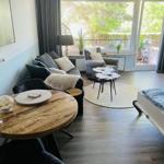 Wohnbereich mit Sofa, Sessel, Tisch und Balkonansicht.