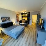 Schlafzimmer mit Bett, Sitzbereich und TV-Möbel.
