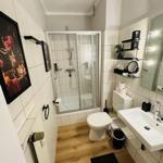 Badezimmer mit Dusche, Toilette und Waschbecken. Holzfußboden und Wandfliesen.