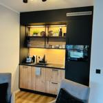 Küchenbereich mit Holzfronten, Edelstahlspüle und integriertem Kühlschrank.