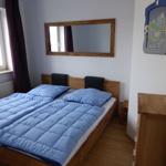 Schlafzimmer mit Doppelbett, Spiegel und Holzmöbel.