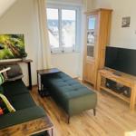 Wohnzimmer mit Sofa, Sitzbank, Fernseher und Holzmöbeln.