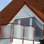 Dachgeschoss balkon mit roten metallgeländer und getöntem glas