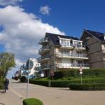 Moderne Mehrfamilienhäuser mit Balkonen und gepflegten Hecken an einer Straße.