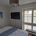 Schlafzimmer mit Bett, TV und Fenster mit Jalousien.