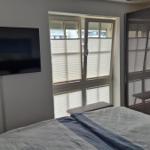 Schlafzimmer mit Bett, TV und Fenster mit Jalousien.