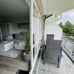 Terrasse mit Tisch und Stühlen. Blick ins Wohnzimmer mit Sofa und Pflanze.