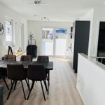 Dining area with table and chairs, kitchen and bedroom in the background.