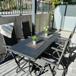 Terrace with table, chairs, plants, and sunshade.