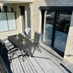 Terrace with table and chairs, plants, and glass sliding doors to the apartment.