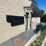 Entrance area with mailbox and house number 77 on a modern stone wall.