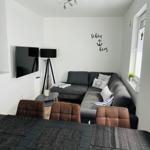 Living and dining area with sofa, TV, and table with chairs.