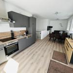 Modern kitchen with dining area and living room in background.