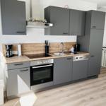 Modern kitchen with gray cabinets, wooden countertop, and built-in stove.