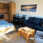 Wohnung mit Schlafzimmer, Küchenzeile und Wohnbereich mit Sofa und Esstisch.